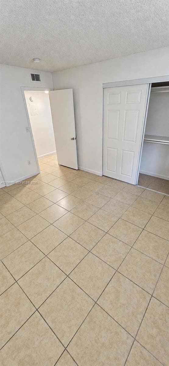 Neutral tile flooring throughout, featuring a multi-panel sliding closet door and a six-panel interior swing door