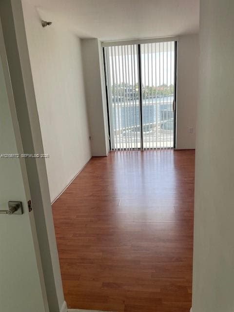 Room featuring wood-finish flooring and sliding glass doors with vertical blinds