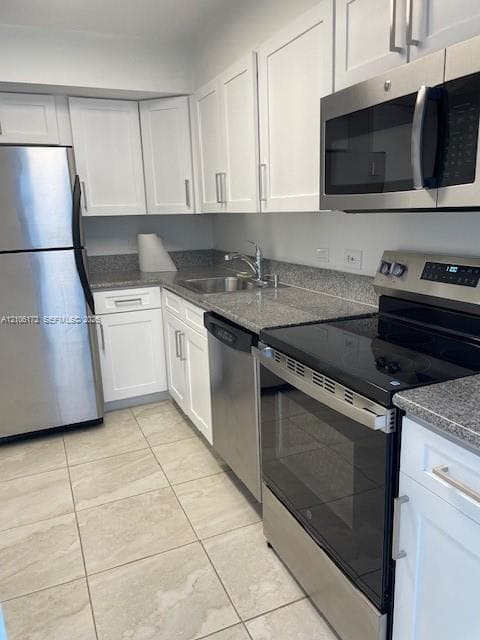 Kitchen featuring white cabinetry, stone-finish countertops, stainless steel appliances, a double-basin undermount sink, and tile flooring
