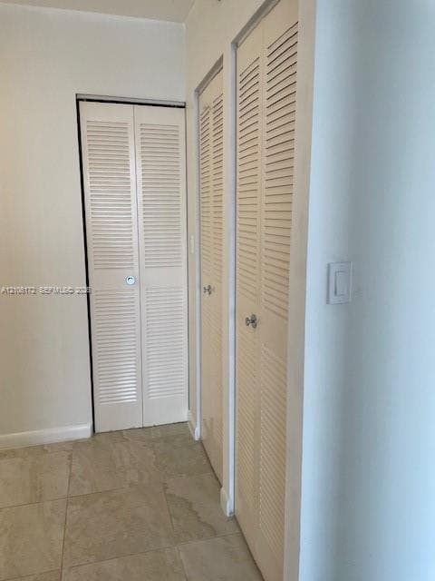 Large-format neutral tile flooring and multiple bi-fold louvered closet doors