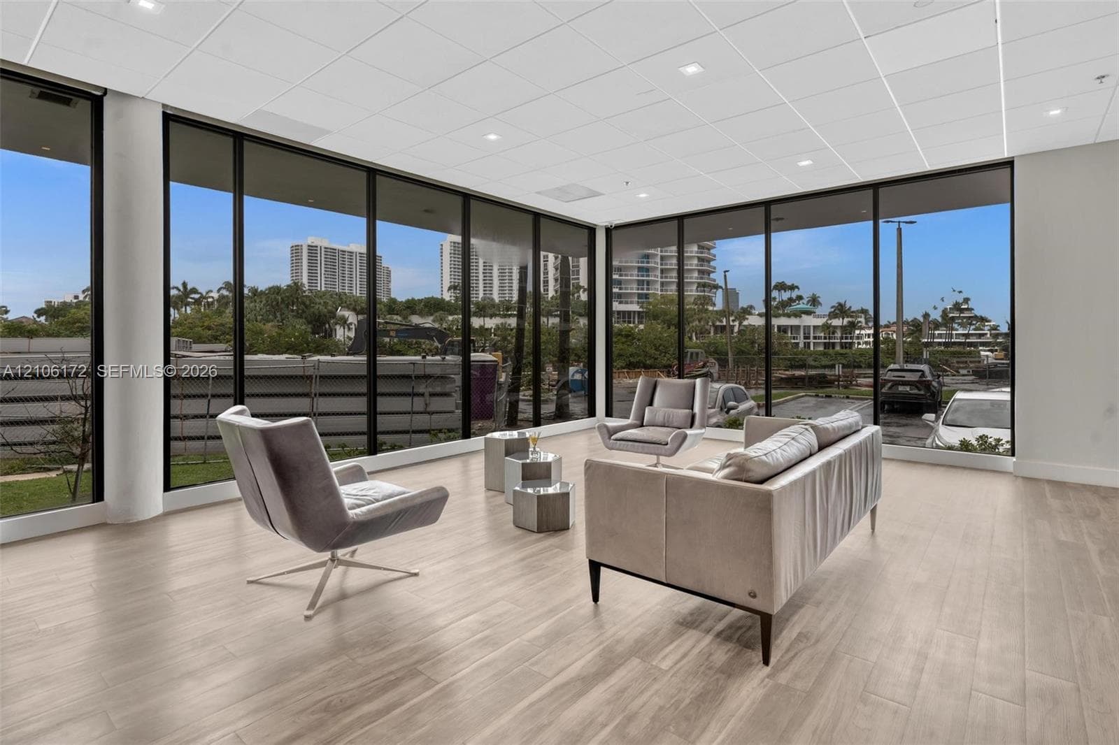 Open-concept room featuring floor-to-ceiling windows with black metal frames, wood-finish flooring, and recessed ceiling lighting