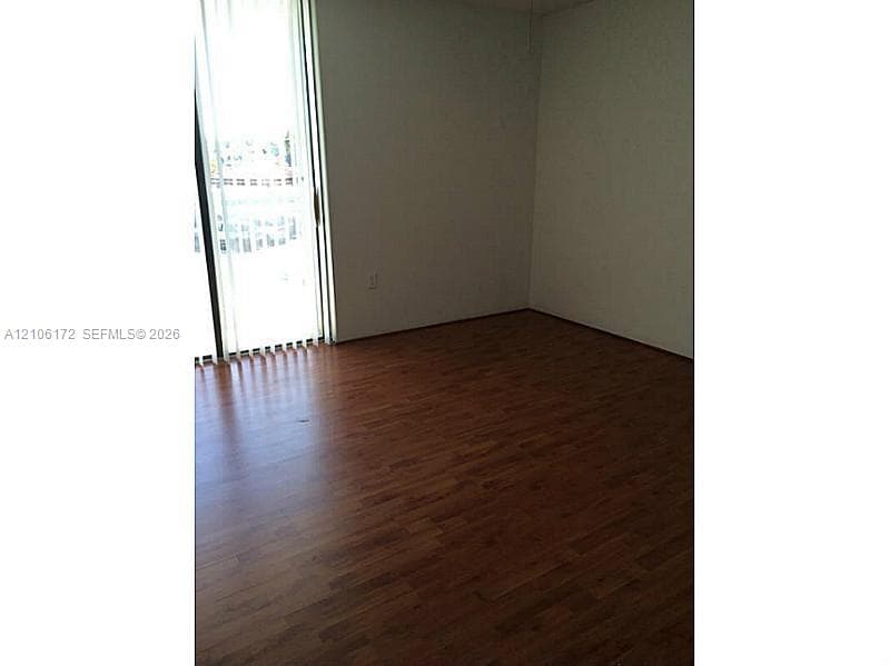 Wood-finish flooring paired with vertical blinds and a sliding glass door