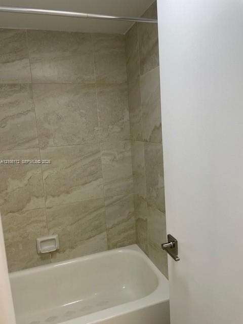 Full-height wall tiling with a natural stone-patterned finish, built-in recessed soap niche, and white acrylic bathtub
