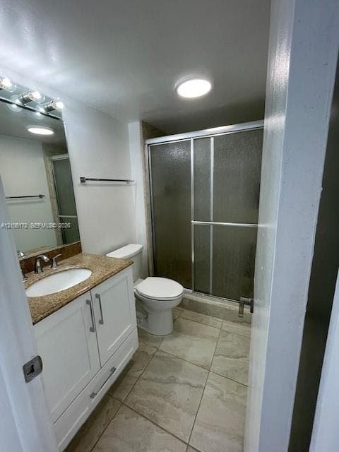 Bathroom featuring white cabinetry, stone-surface vanity top with an integrated sink, tiled flooring, and a walk-in shower with a sliding glass enclosure