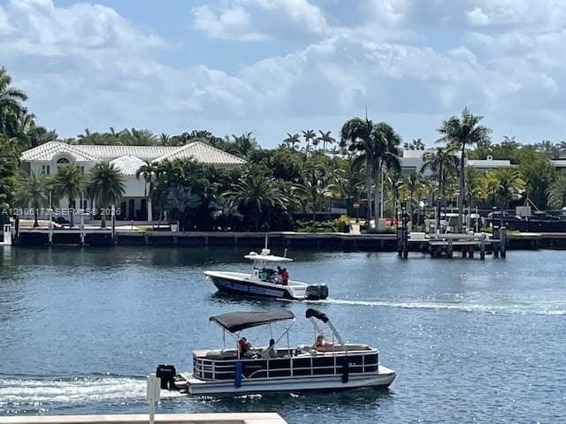 Waterfront property featuring a private boat dock and mature palm tree landscaping