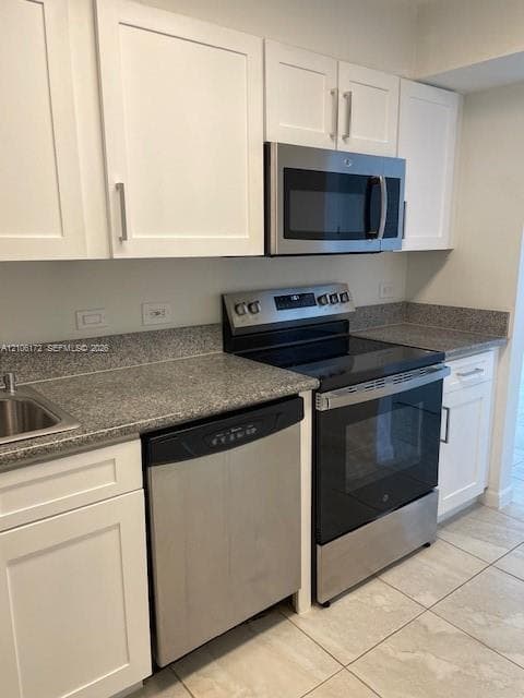 White shaker-style cabinetry, stone-finish countertops, stainless steel appliances, and tiled flooring