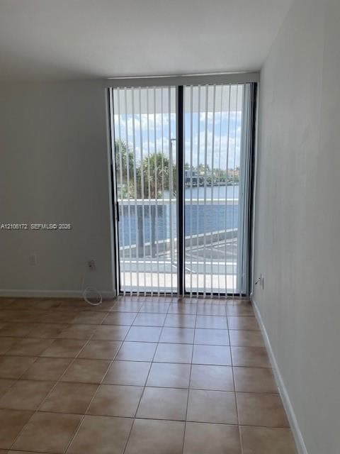Ceramic tile flooring and sliding glass doors with vertical blinds, featuring water frontage and balcony access