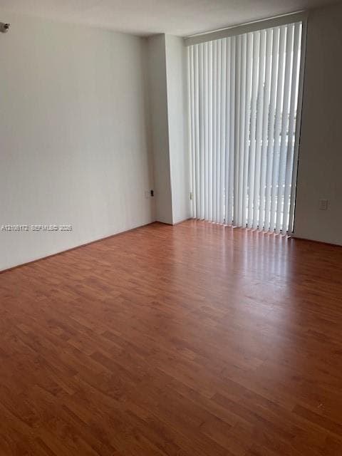 Wood-finish flooring and floor-to-ceiling sliding glass doors with vertical blinds