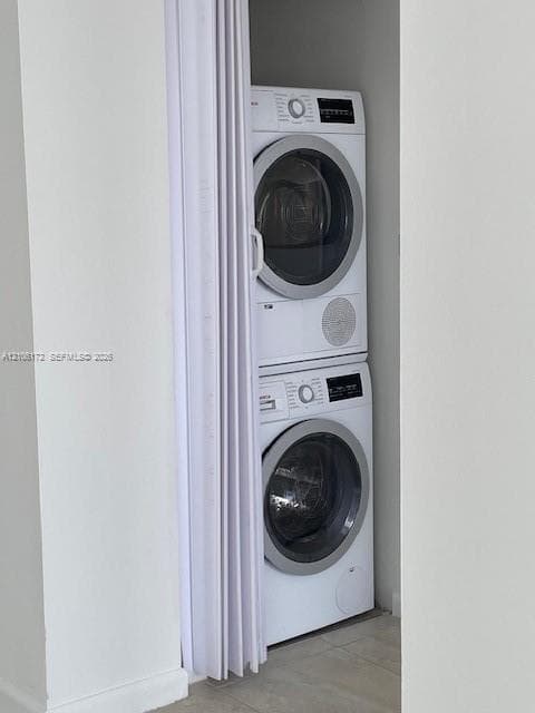 Stacked white front-load washer and dryer set concealed by a folding white privacy door