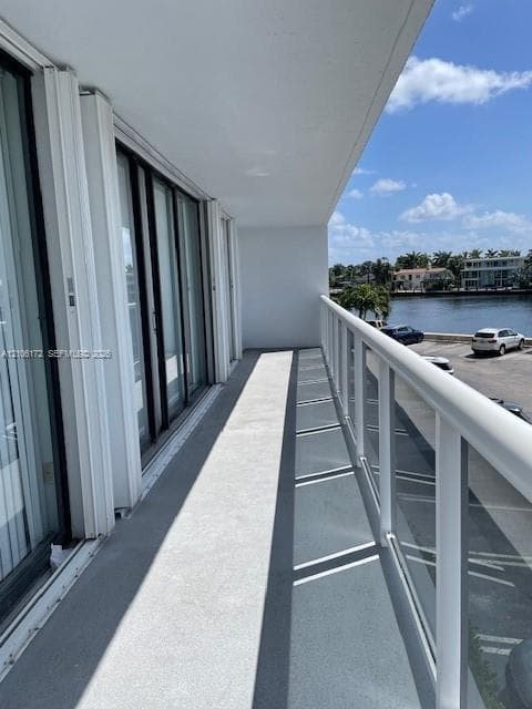Private balcony featuring a concrete floor, glass panel railing, and metal frame, accessible via multiple sliding glass doors