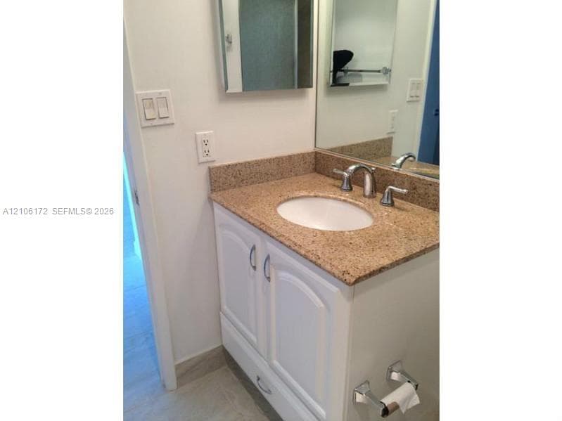 Vanity featuring a stone-composite countertop, white shaker-style cabinetry, an integrated oval basin, and a dual-handle chrome faucet