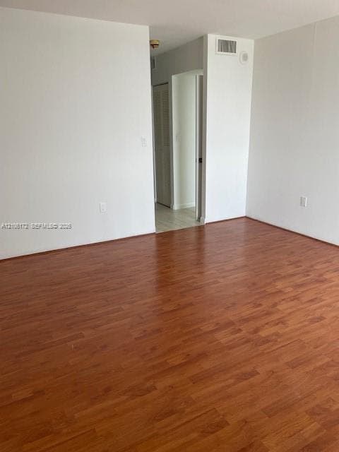 Interior space featuring wood-finish flooring, white walls, and a louvered closet door