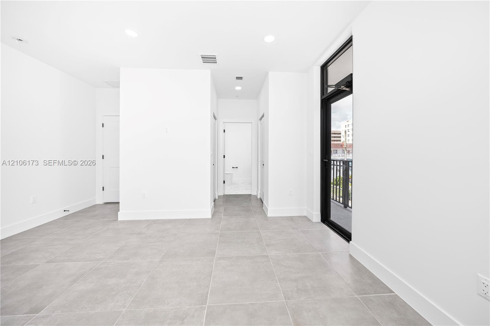 Interior featuring large-format ceramic tile flooring, recessed lighting, and a full-height glass door with a black frame