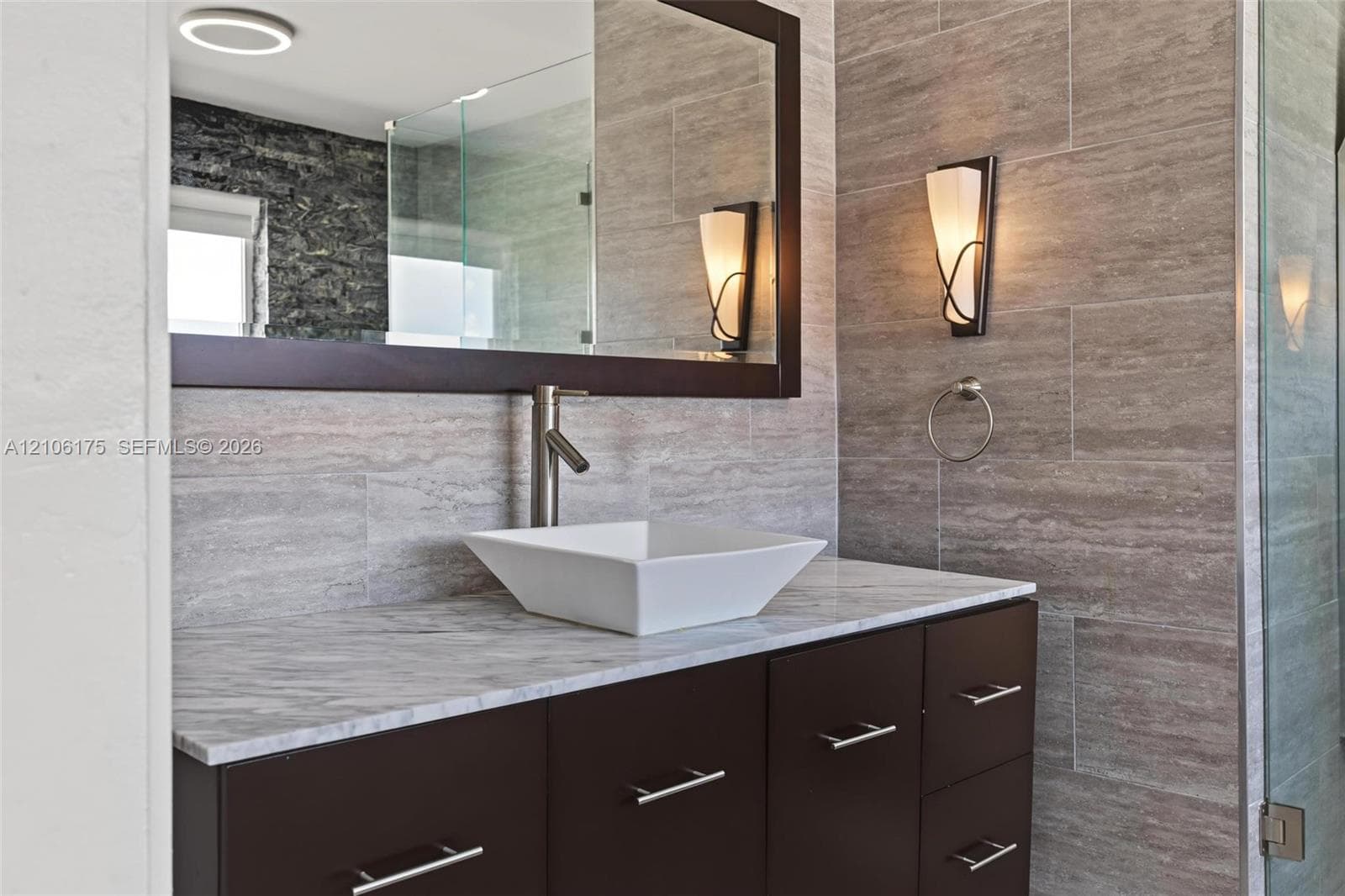 Custom vanity featuring a neutral stone countertop, vessel sink, and rectangular mirror