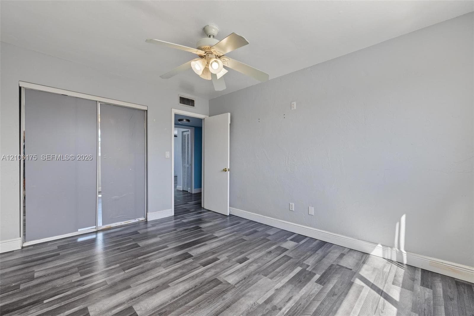 Wood-finish flooring, ceiling fan with integrated lighting, and dual-panel sliding closet doors