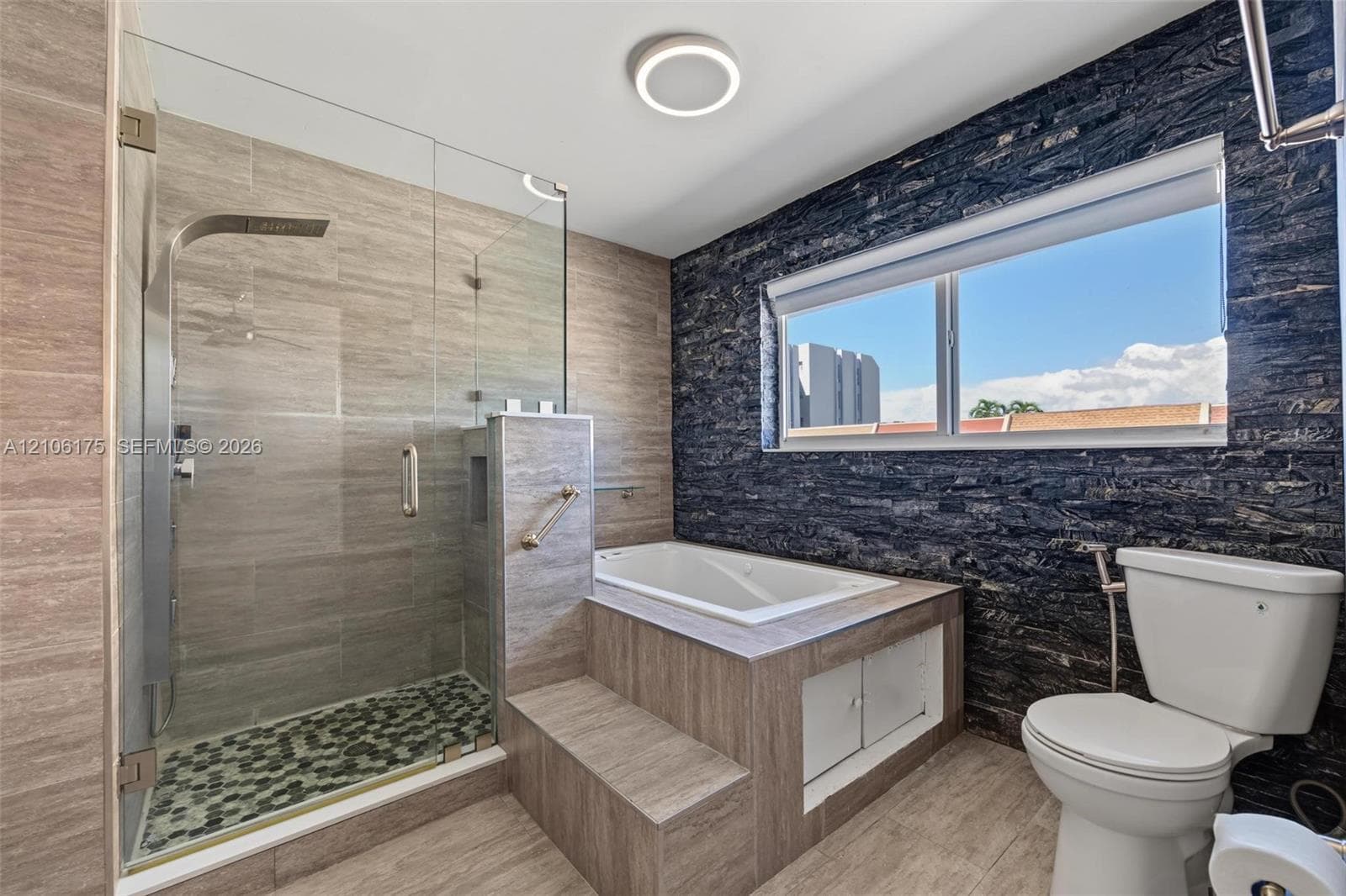 Walk-in shower with a glass enclosure, built-in soaking tub featuring a stepped surround, textured slate-style wall accents, and neutral tile flooring
