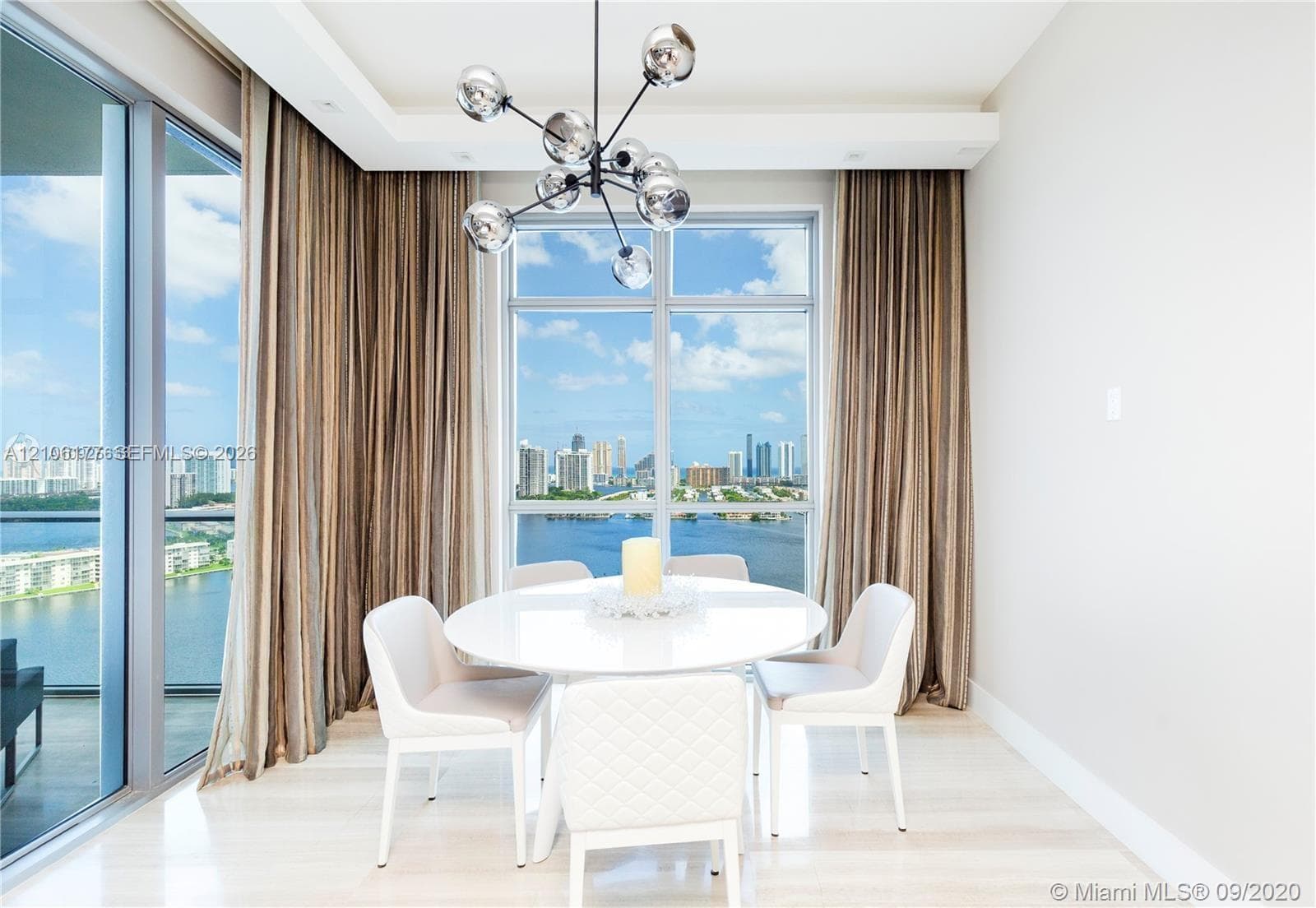 Floor-to-ceiling windows, sculptural multi-globe pendant light, tray ceiling, and light-toned wood-finish flooring