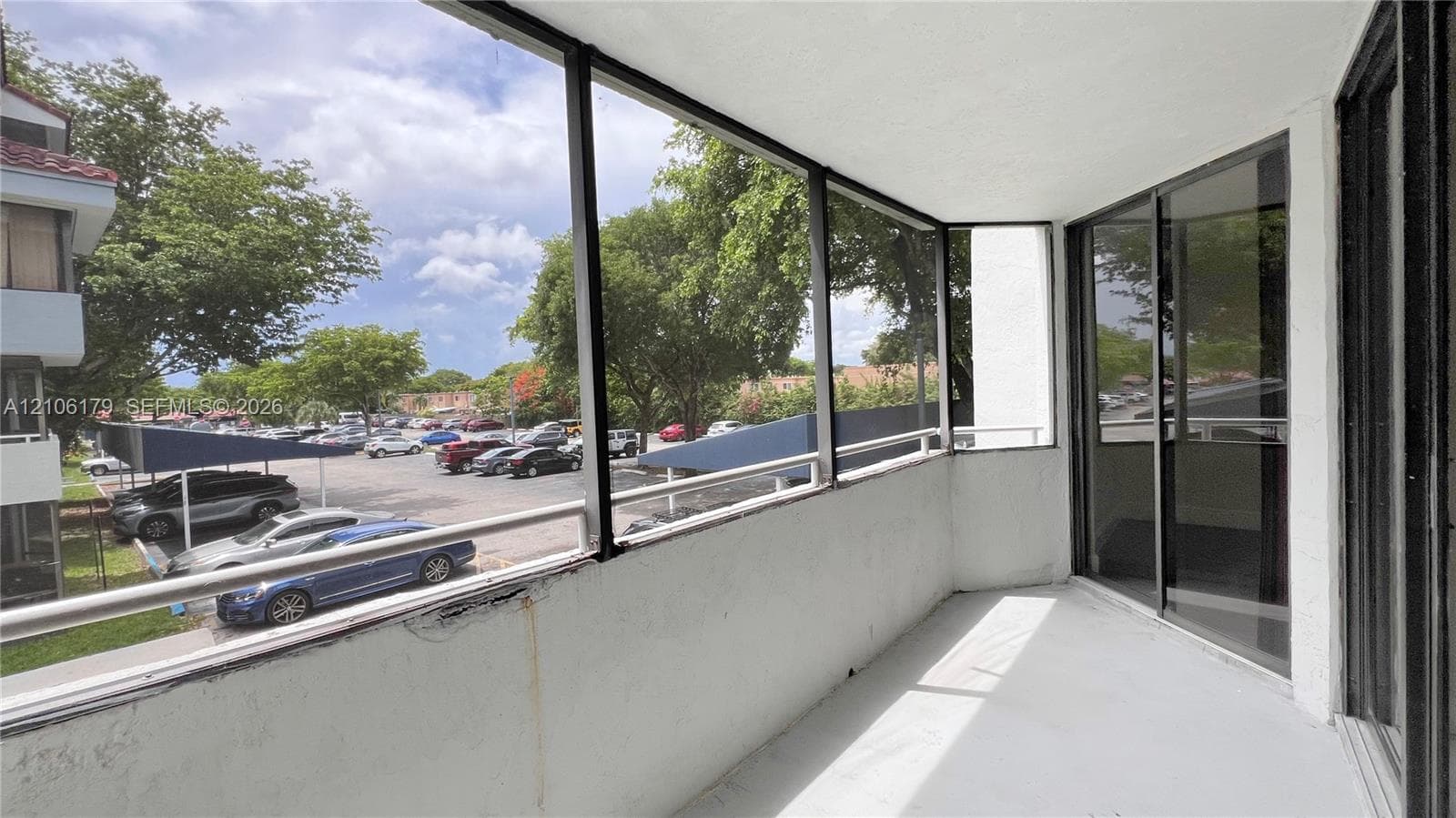 Screened-in balcony featuring a concrete floor, metal railings, and sliding glass door access