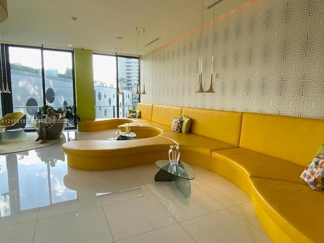 Common area featuring large-format tile flooring, built-in curved bench seating, floor-to-ceiling windows, and decorative patterned wallpaper