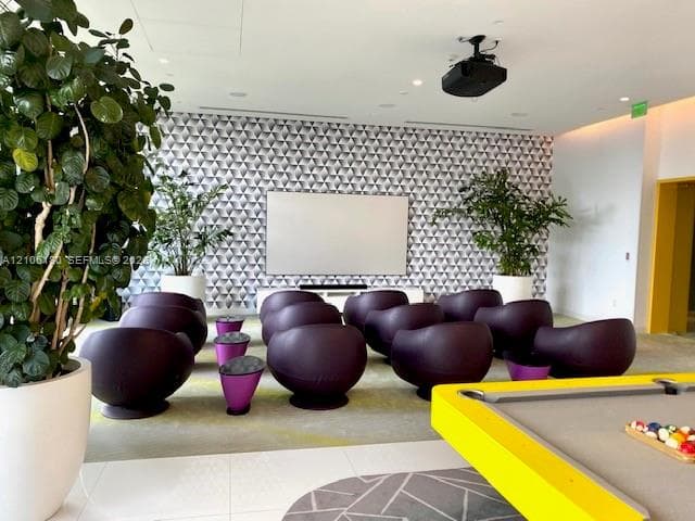 Media room featuring geometric patterned wall coverings, a large wall-mounted projection screen, and ceiling-mounted projection equipment
