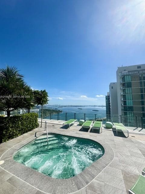 Rooftop spa with tile surround, glass perimeter railing, and concrete-style tile decking, featuring expansive water scenery