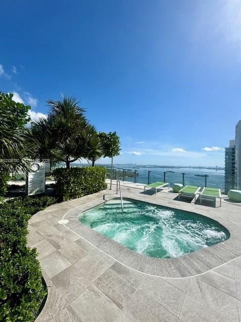 Rooftop spa featuring natural stone decking, integrated greenery, and a glass perimeter railing overlooking the water