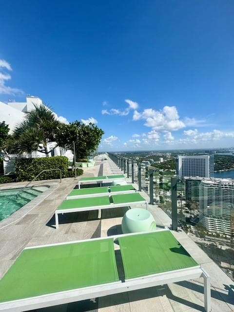 Rooftop terrace featuring a swimming pool, stone-tile flooring, and glass panel railing