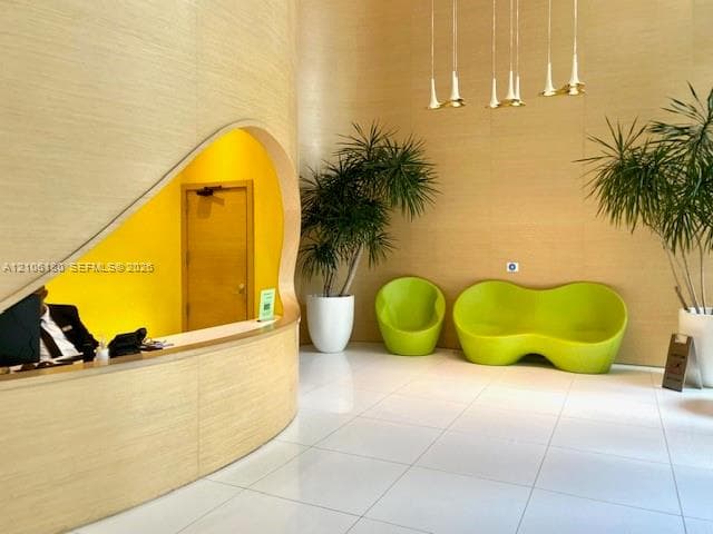 Curved wood-paneled reception desk with an organic cutout design, high ceilings, large-format tile flooring, and multi-pendant lighting