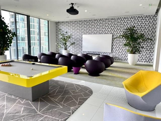 Floor-to-ceiling windows, geometric patterned accent wall, recessed ceiling lighting, and tile flooring