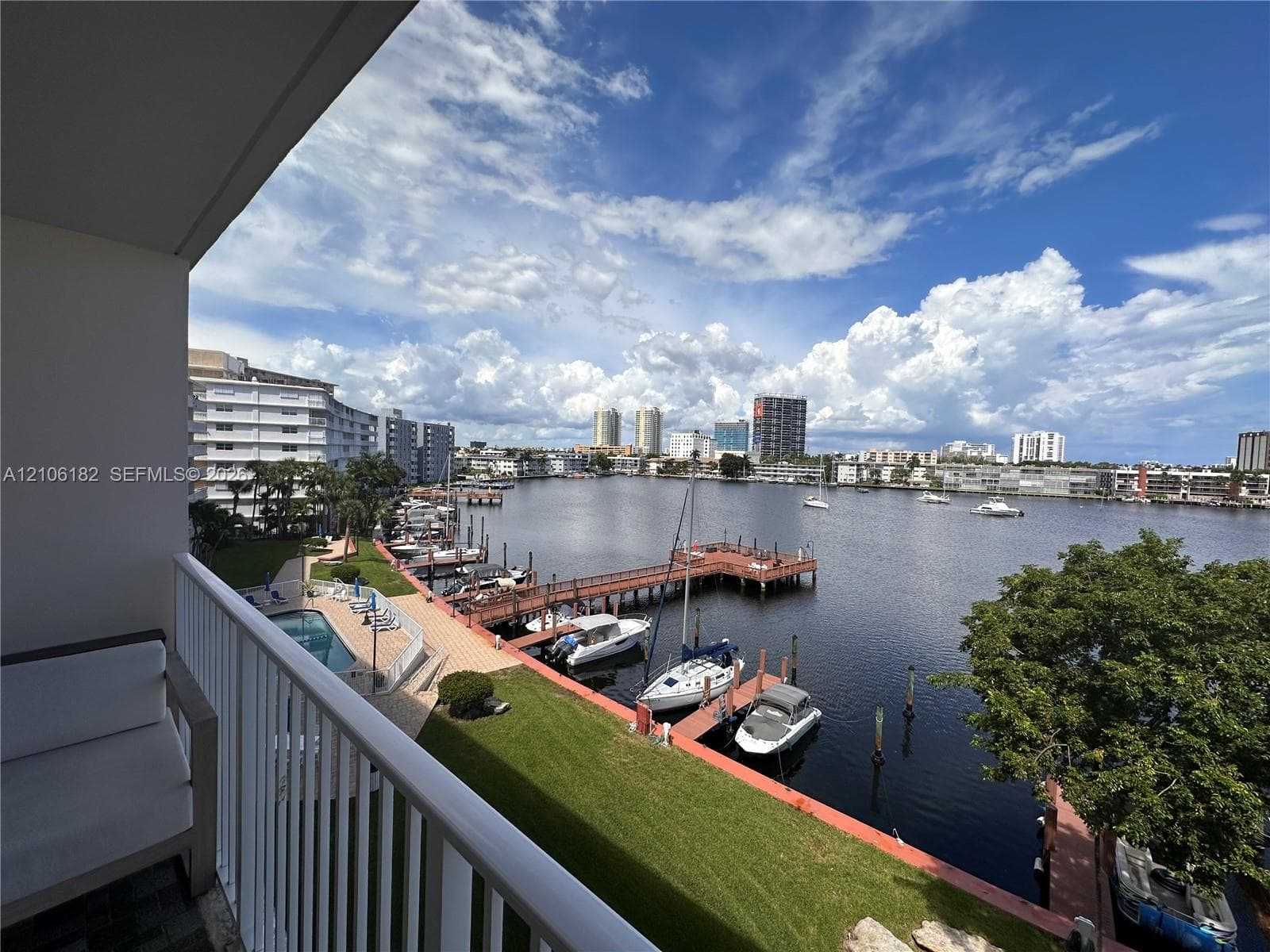 Private balcony with a metal railing overlooking the waterway, featuring a dock, boat slips, and an inground swimming pool