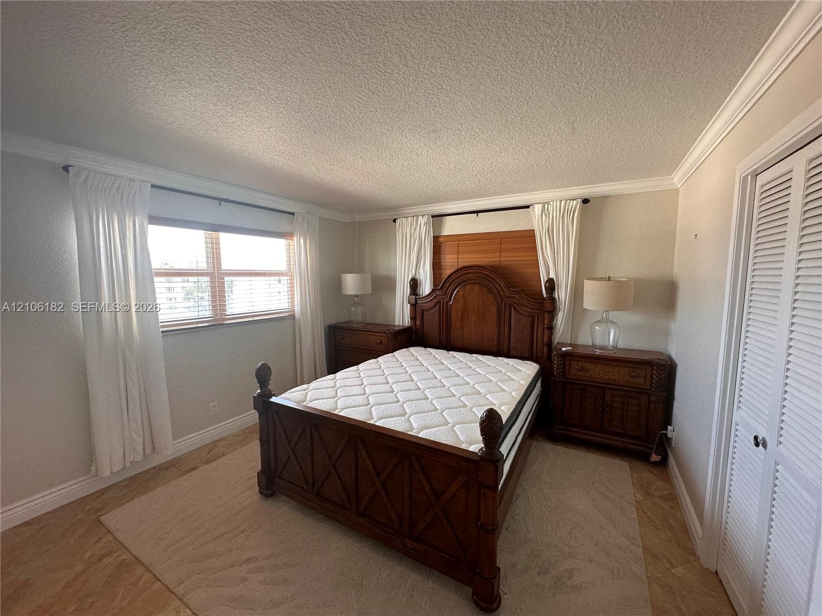 Room featuring wood-finish flooring, crown molding, and louvered bi-fold closet doors