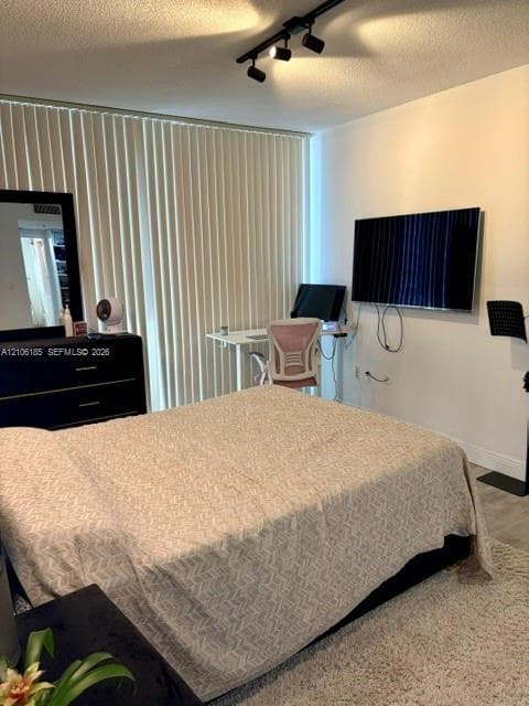 Neutral interior space featuring vertical window blinds, wall-mounted television hardware, and overhead track lighting