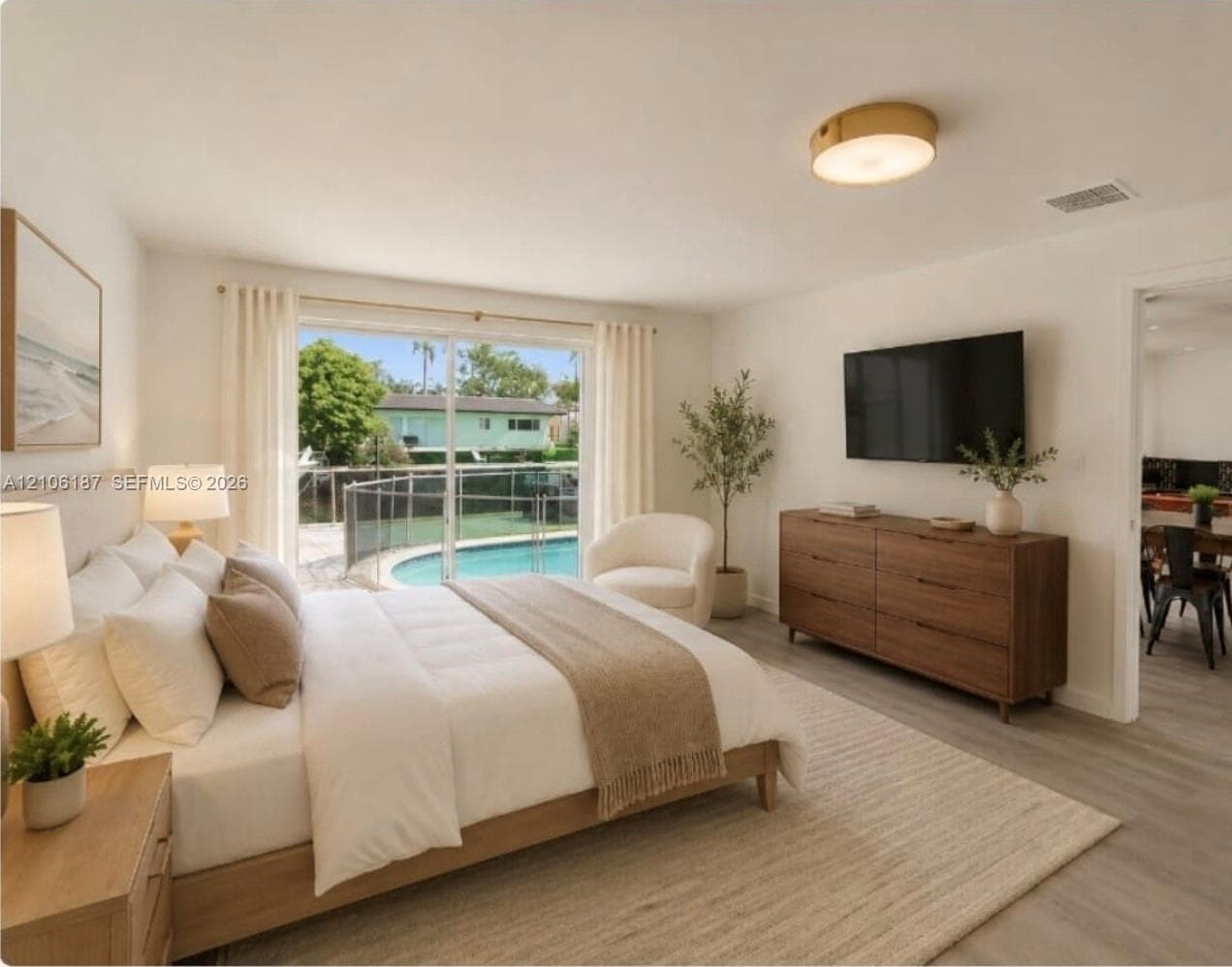 Sliding glass doors opening to an exterior pool with metal railing, wood-finish flooring, and a circular flush-mount ceiling light