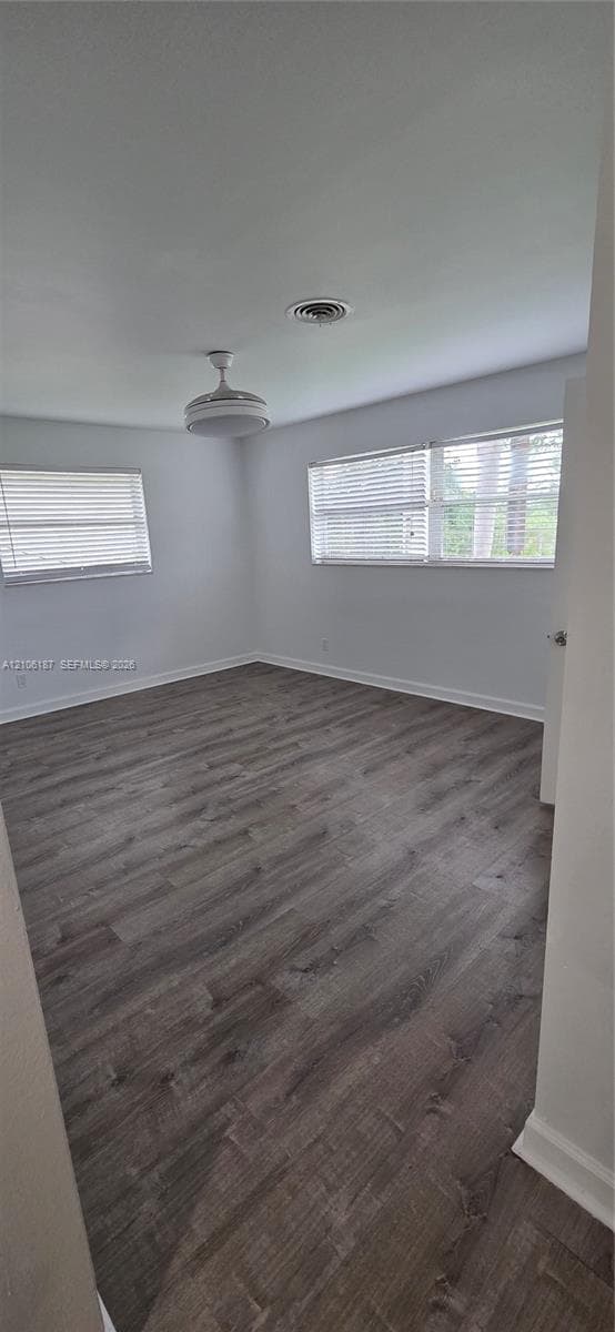 Interior space featuring wood-finish flooring, neutral wall paint, multi-pane windows with horizontal blinds, and a ceiling-mounted light fixture