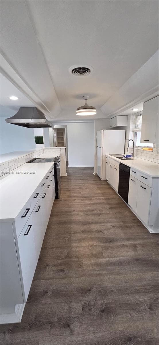 Kitchen featuring white shaker-style cabinetry, solid-surface countertops, wood-finish flooring, a stainless steel range hood, and tile backsplash
