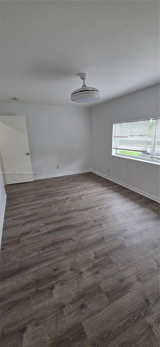 Interior room featuring wood-finish flooring, a horizontal multi-pane window, and a white ceiling-mounted fan with an integrated light fixture