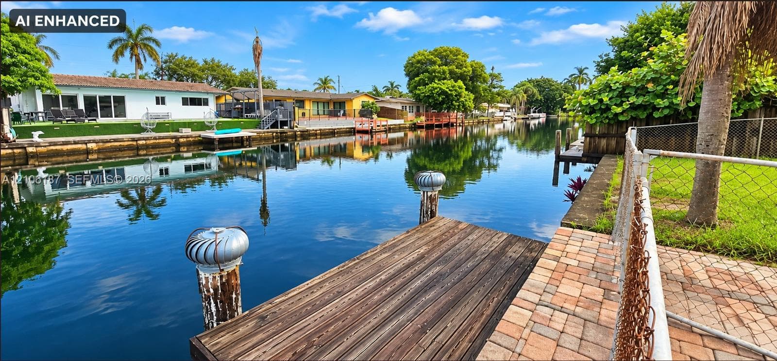 Waterfront property featuring a wood-plank dock, canal access, and stone paver patio