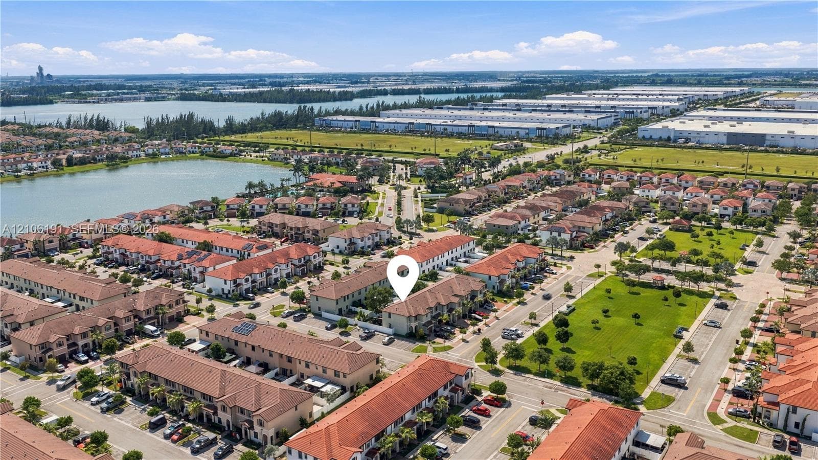 Aerial perspective of residential community featuring terra-cotta tile roofing, stucco exterior siding, paved street access, and water features