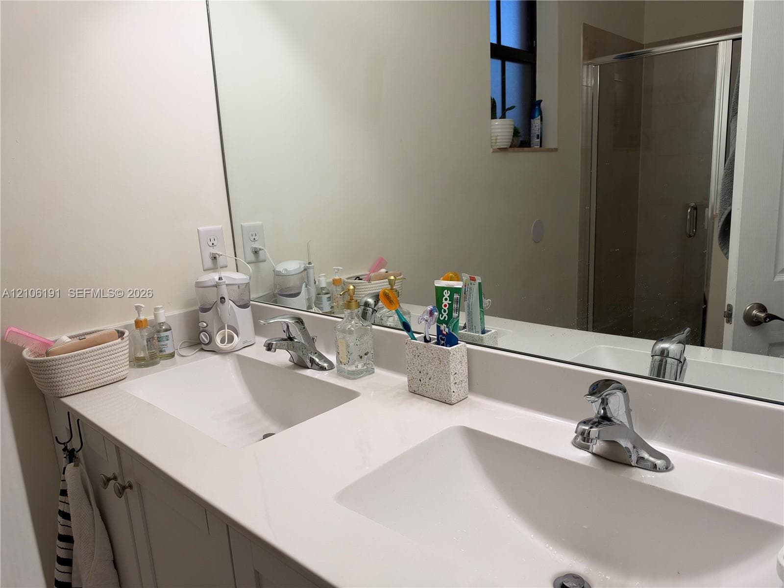 Dual-sink vanity with white countertop, integrated basin sinks, chrome faucets, and large wall-mounted mirror