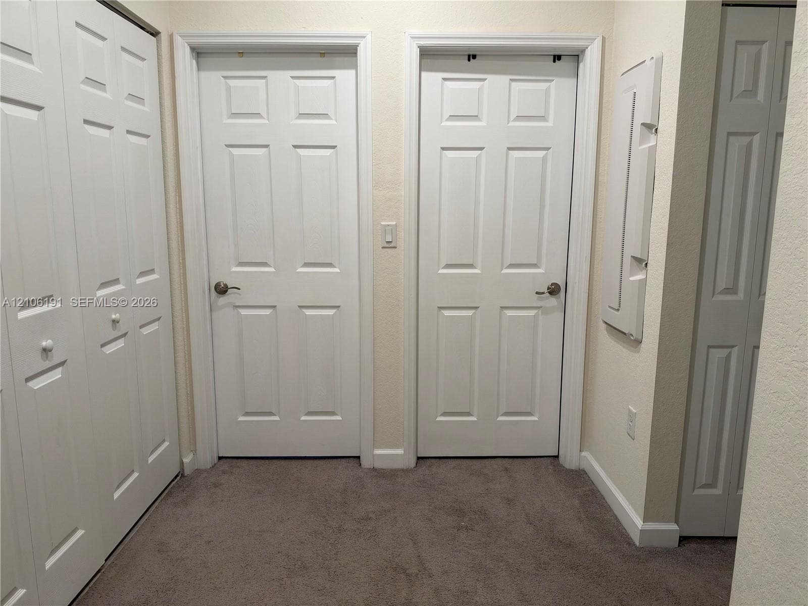 Interior space featuring neutral wall-to-wall carpeting, multiple six-panel interior doors, and built-in closet storage with bi-fold doors