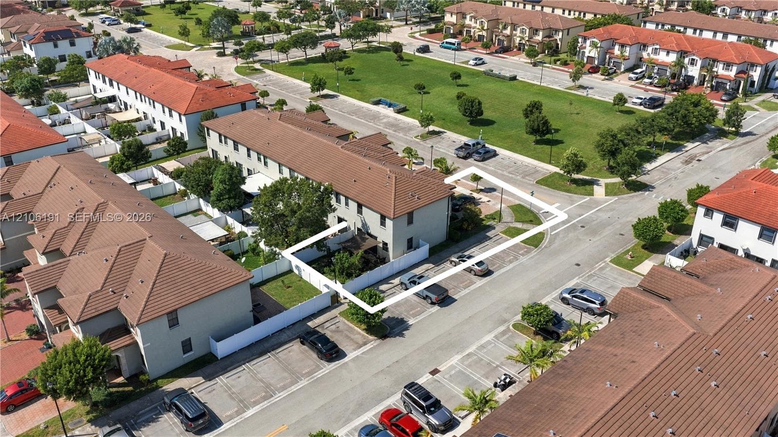 Aerial perspective of a multi-story residence featuring a tile roof, enclosed fenced yard, and dedicated surface parking