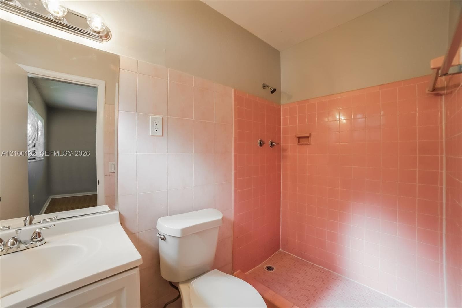 Bathroom featuring ceramic wall tiling, white vanity with integrated sink, chrome-finished hardware, and walk-in shower enclosure