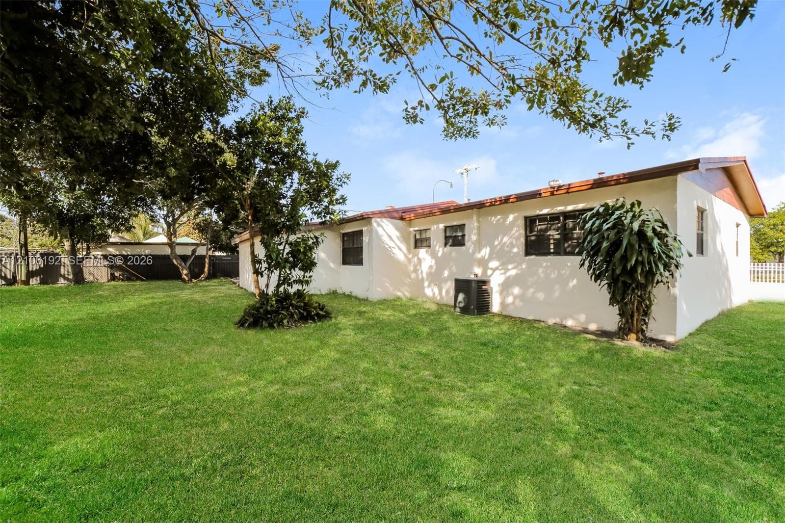 Expansive backyard featuring a level lawn, mature trees, and a fenced perimeter
