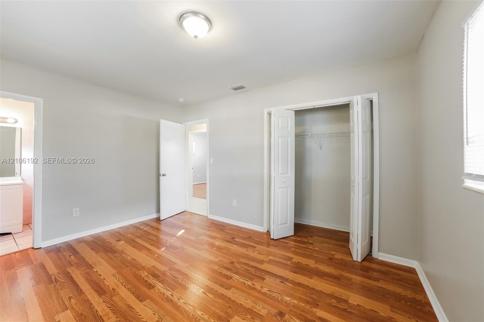 Interior space featuring wood-finish flooring, neutral wall paint, and a built-in closet with double-panel doors