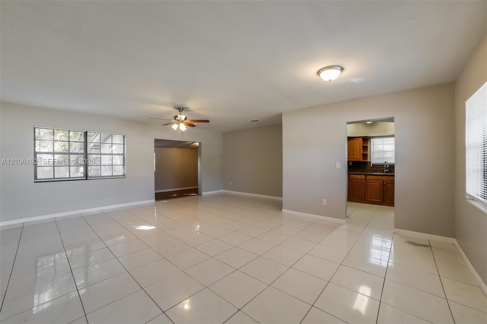 Spacious interior featuring large-format tile flooring, recessed and ceiling-mounted lighting, a multi-blade ceiling fan, and windows with integrated blinds