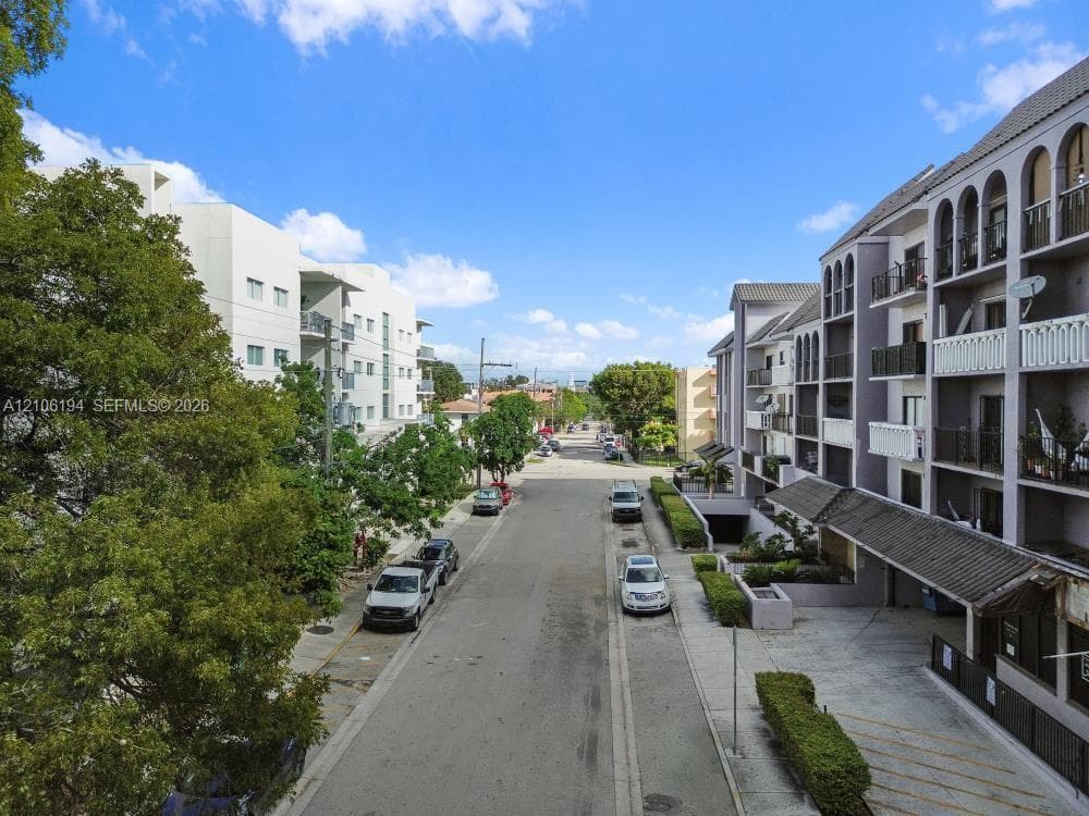 Multi-story residential building exterior featuring arched architectural detailing, private balconies, and covered parking access