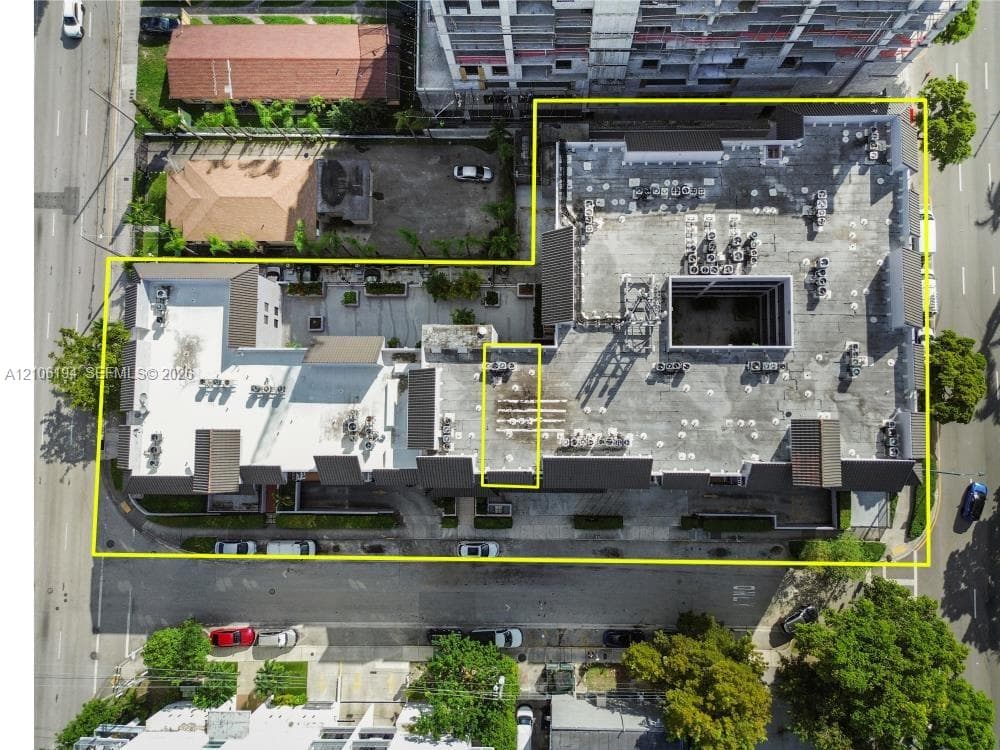 Aerial perspective of the property featuring a multi-level flat roof structure with dark shingled accents and an internal courtyard