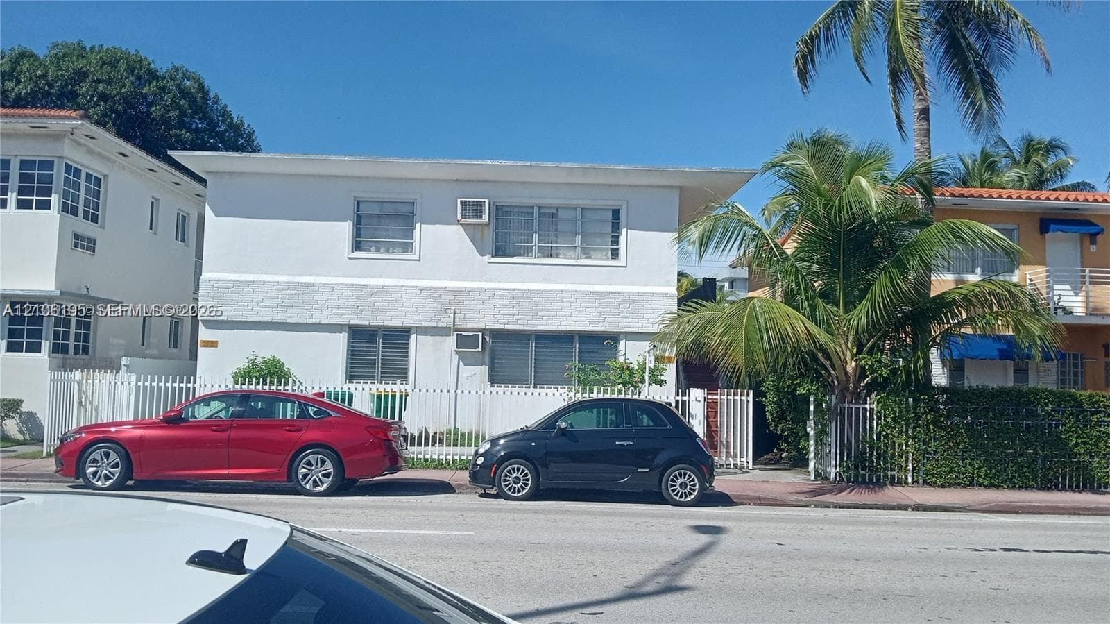 Two-story exterior featuring a white stucco facade, horizontal slider windows, and a perimeter fence