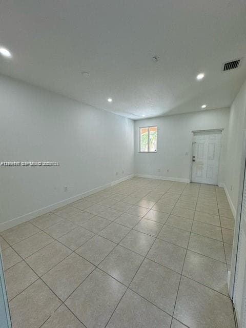 Neutral-toned tile flooring, recessed ceiling lighting, and a multi-panel entry door