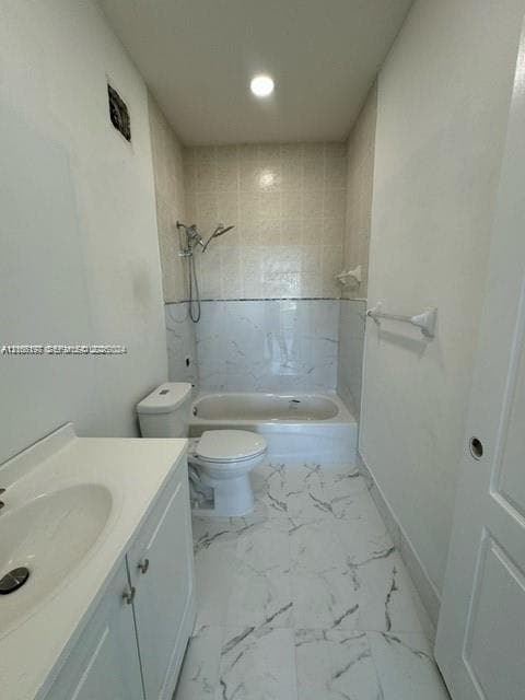 Bathroom featuring a white vanity cabinet, composite countertop with integrated sink, porcelain tile flooring with veining, and a tiled tub-shower surround with a handheld shower fixture